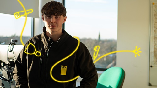 Trade apprentice George in an L&Q jacket, standing in an office with tool-themed yellow digital overlays. 