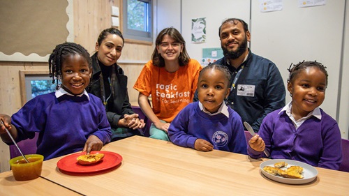 Children enjoying breakfast at school with Magic Breakfast volunteers supporting the meal program.