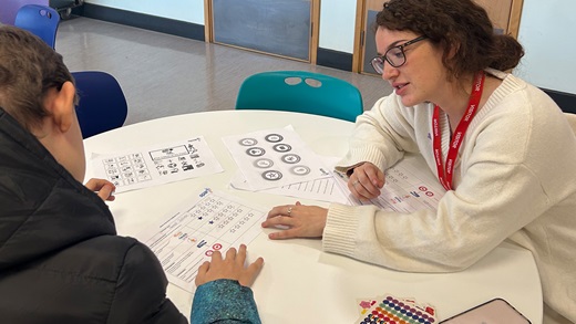 Student working with tutor. Sat around round table.