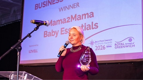 Woman holding a business award and speaking on stage during the Royal Greenwich Business Awards ceremony after being announced as a winner.