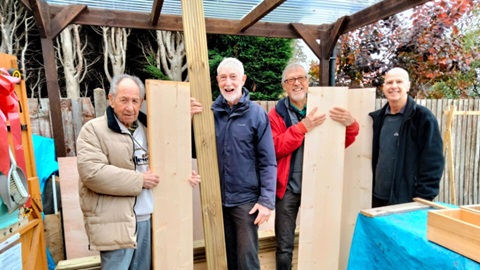 Four men holding planks of wood