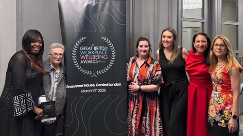 6 L&Q staff surrounding a banner that say's 'The Great British workplace wellbeing awards' and 'Grosvenor House, Central London, March 19th 2026'