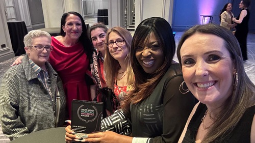 6 L&Q staff taking a selfie together and holding their award. The award has the name 'The Great British wellbeing awards' written on it and '2026 Winner'