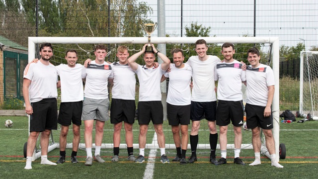 A football team stood with a trophy
