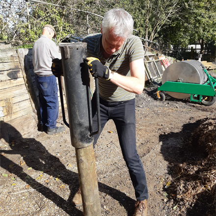 Christopher using a fence post driver