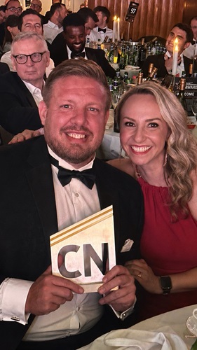 Two colleagues holding award at event night.
