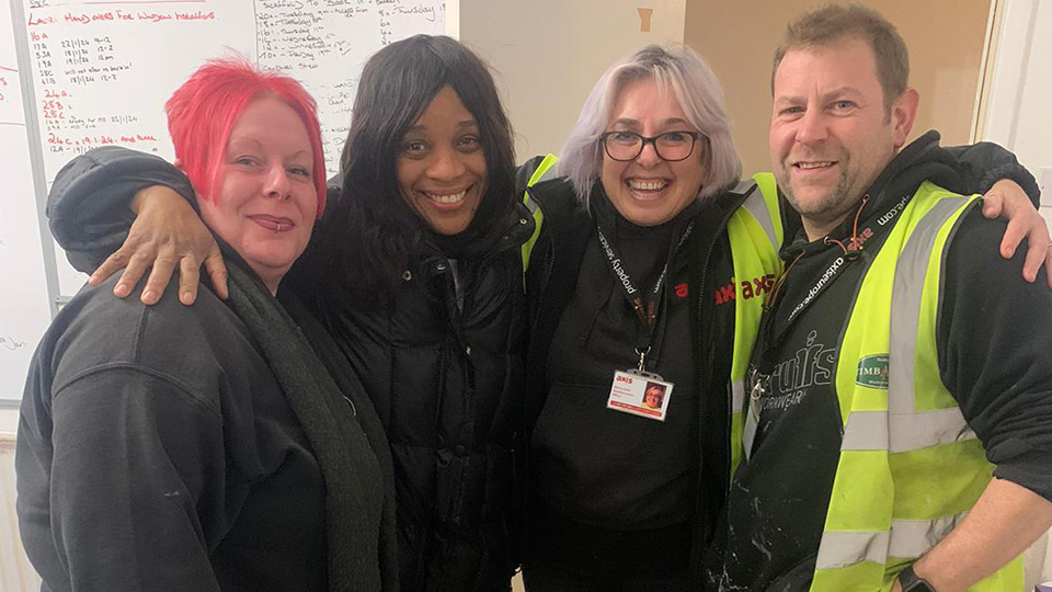 Resident Ms Thomas stood in group photo smiling with three Axis team members