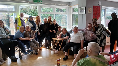 Residents and visitors together in a care home lounge during a community event.