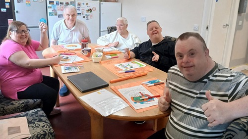 People seated around a table colouring and completing arts activities at a care home.