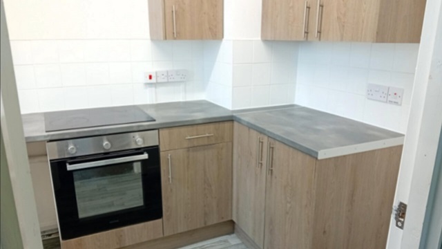 Newly refurbished kitchen with wooden cabinets, grey worktops, tiled backsplash, and a modern oven with hob