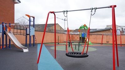 Colourful play area featuring slides, a basket swing, and baby swings for children's enjoyment