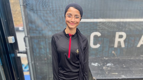 Mumtaz smiling in Salaam Peace sportswear, posing in front of urban background.