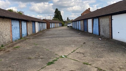 South Buck home area before. A row of garages with blue doors on both sides of a concrete driveway