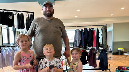 L&Q resident with his family stood in public hall with racks of school uniforms