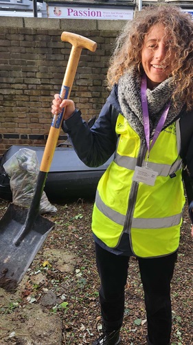 Volunteer holding shovel up in the air in garden