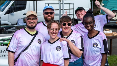 Six Union Manchester FC team members in light pink jerseys, smiling outdoors.
