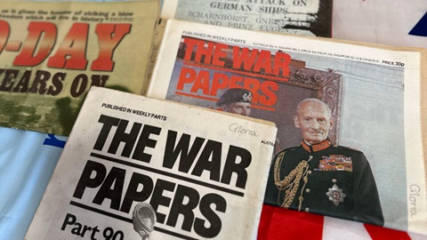 Assorted vintage “The War Papers” newspapers displayed on a table