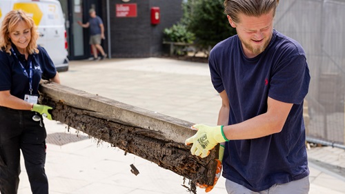 Volunteers carrying a wooden planter beam during improvements to the Walthamstow Stadium community garden.