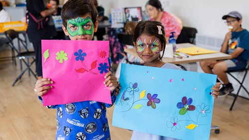 Children holding flower-themed craft creations at the Walthamstow Stadium Summer Biodiversity Fest.
