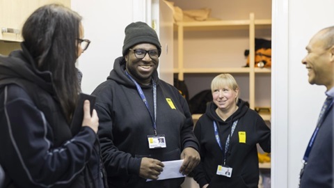 Group of colleagues smiling and talking inside a training hub room, wearing L&Q hoodies.