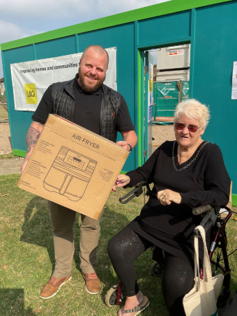A man holding an air fryer stood next to a woman in a wheelchair
