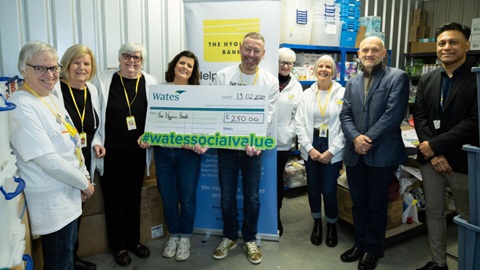 A group of volunteers from The Hygiene Bank and representatives from Wates posing with a large donation cheque for £250