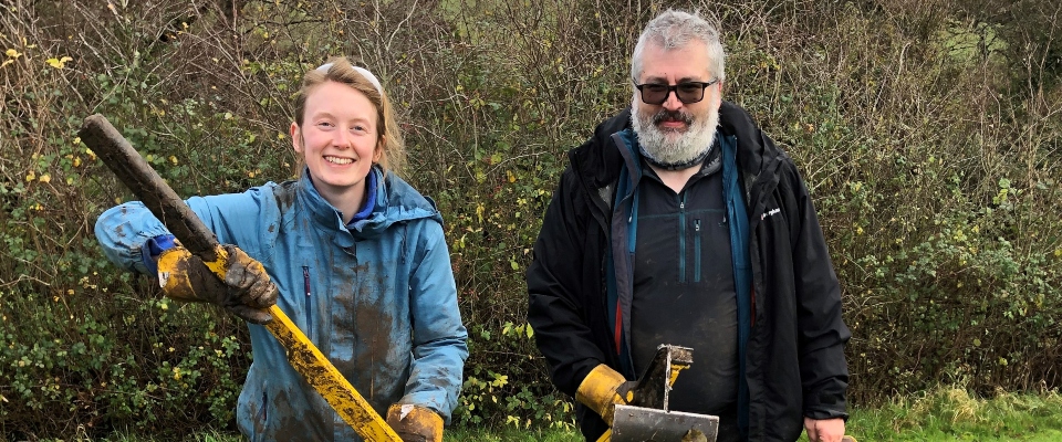 A man and a woman in a field with tools