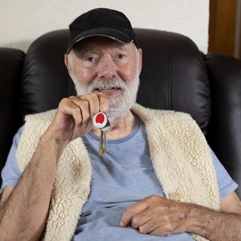 An elderly man holding a pendant