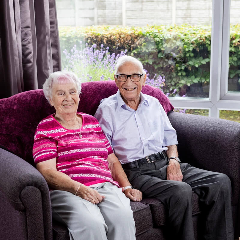 An elderly couple sat on a sofa