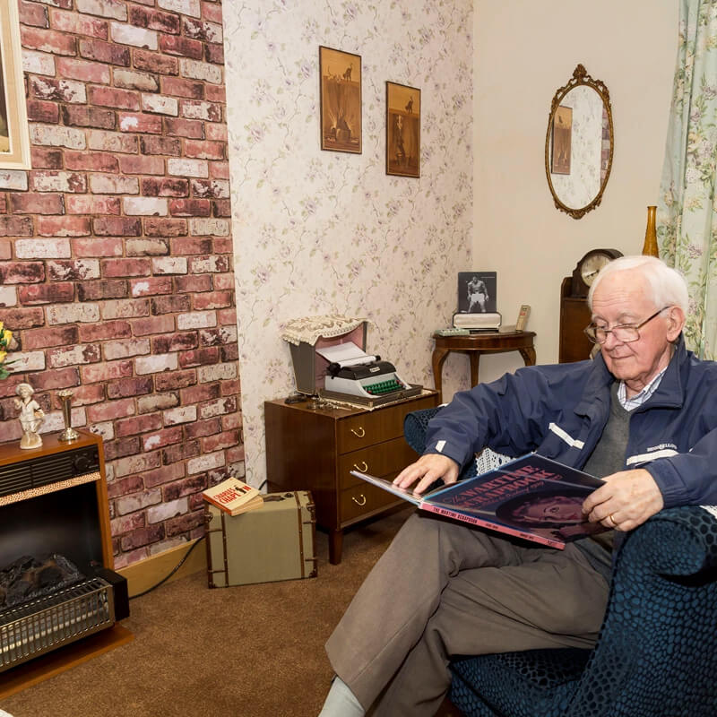 An elderly man reading a book in an armchair