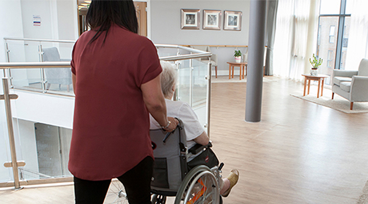 Carer pushing older woman in wheelchair