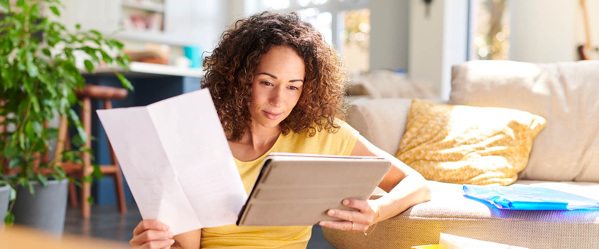 Woman looking at paper bill and tablet device