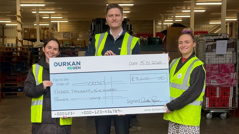 Durkan Regen team presenting a large cheque donation to Crisis at a warehouse.