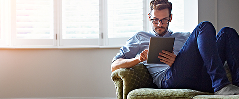 man on sofa looking at ipad