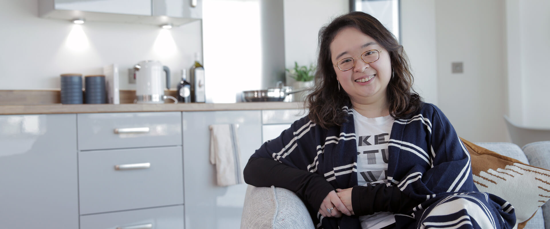 Woman sat on sofa in her kitchen